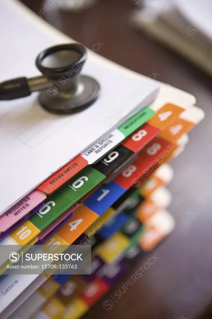 A stethoscope on top of a stack of patient files