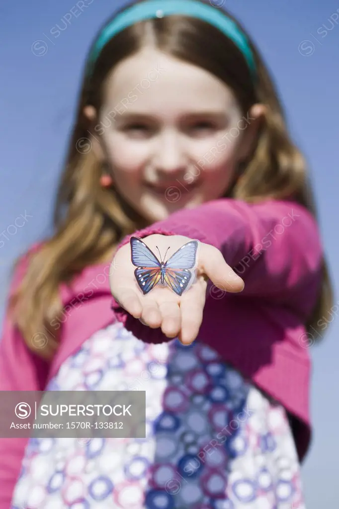 A girl holding a plastic butterfly in her hand
