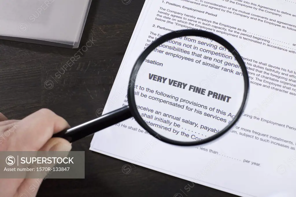 Examining the fine print of an employment agreement with a magnifying glass
