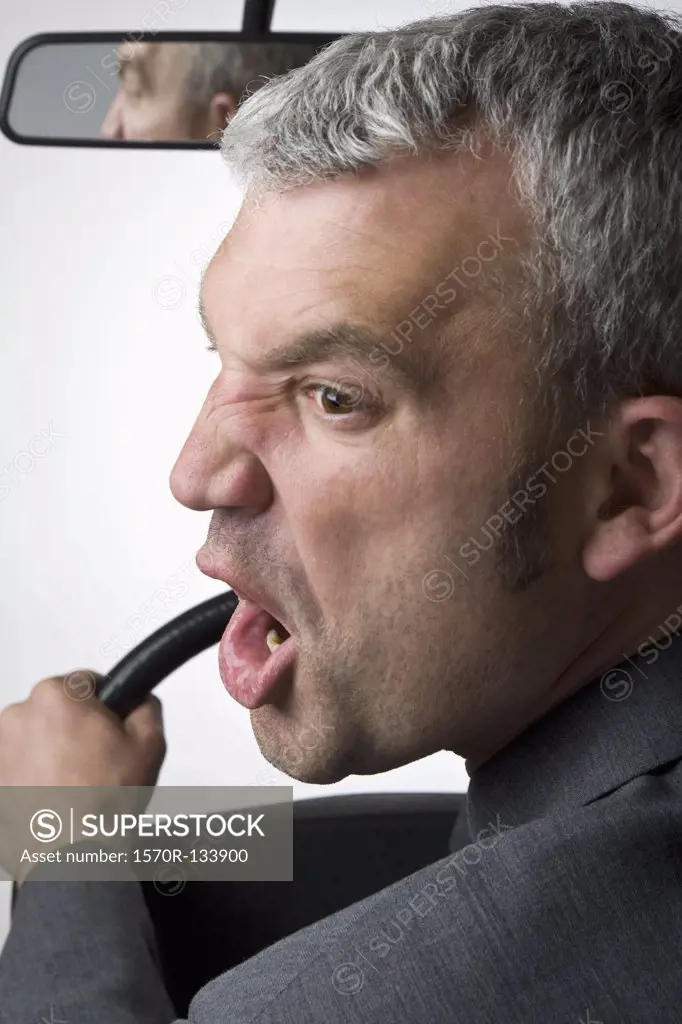 A man yelling over his shoulder whilst driving a car