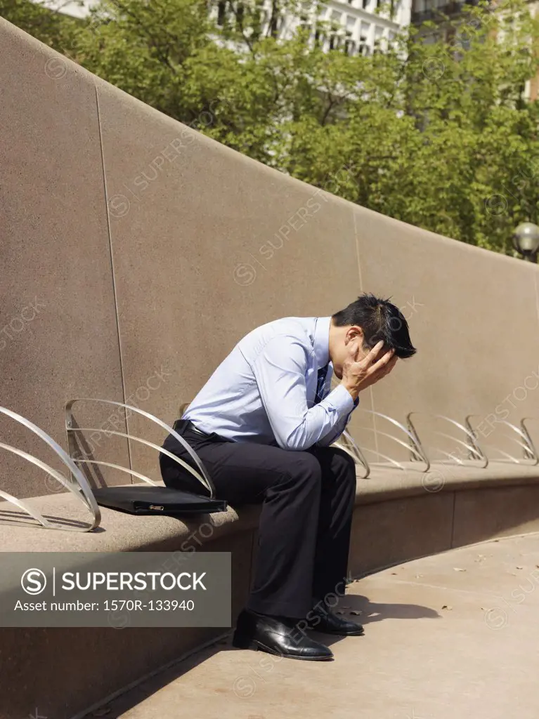 A distraught businessman with his head in hands