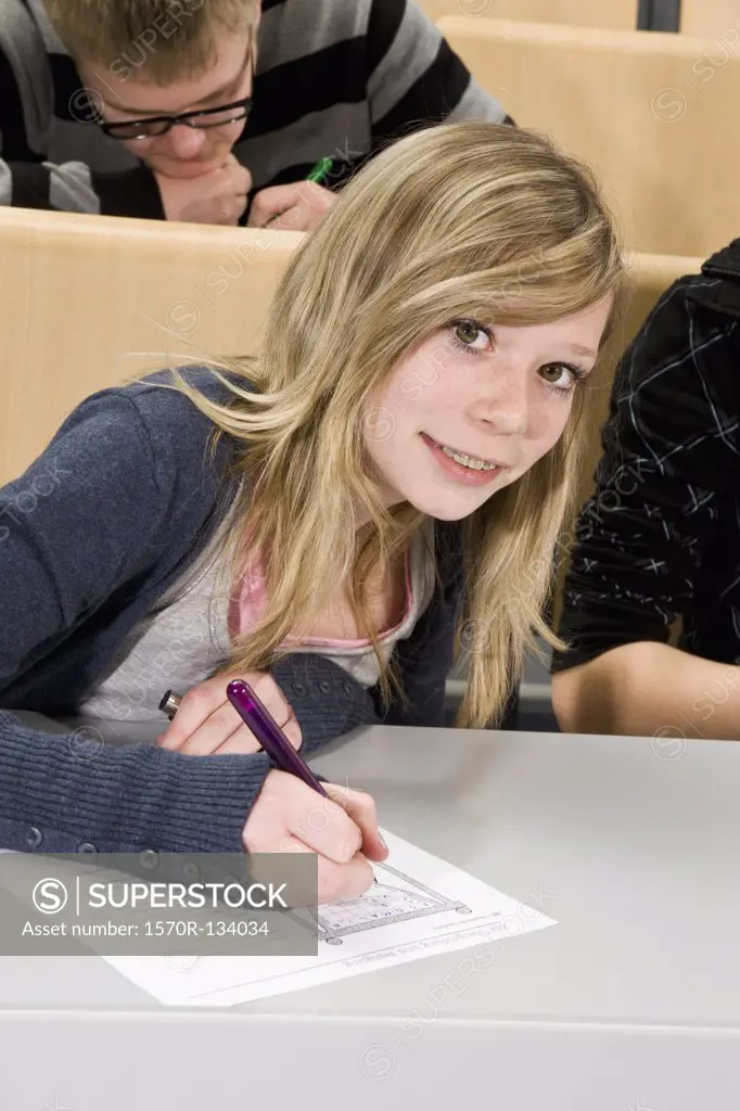 Portrait of a teenager doing a worksheet in class, smiling at camera