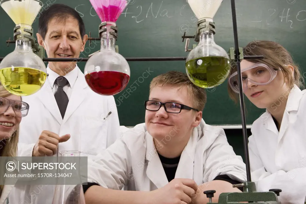 A teacher supervising two students conducting a chemistry experiment