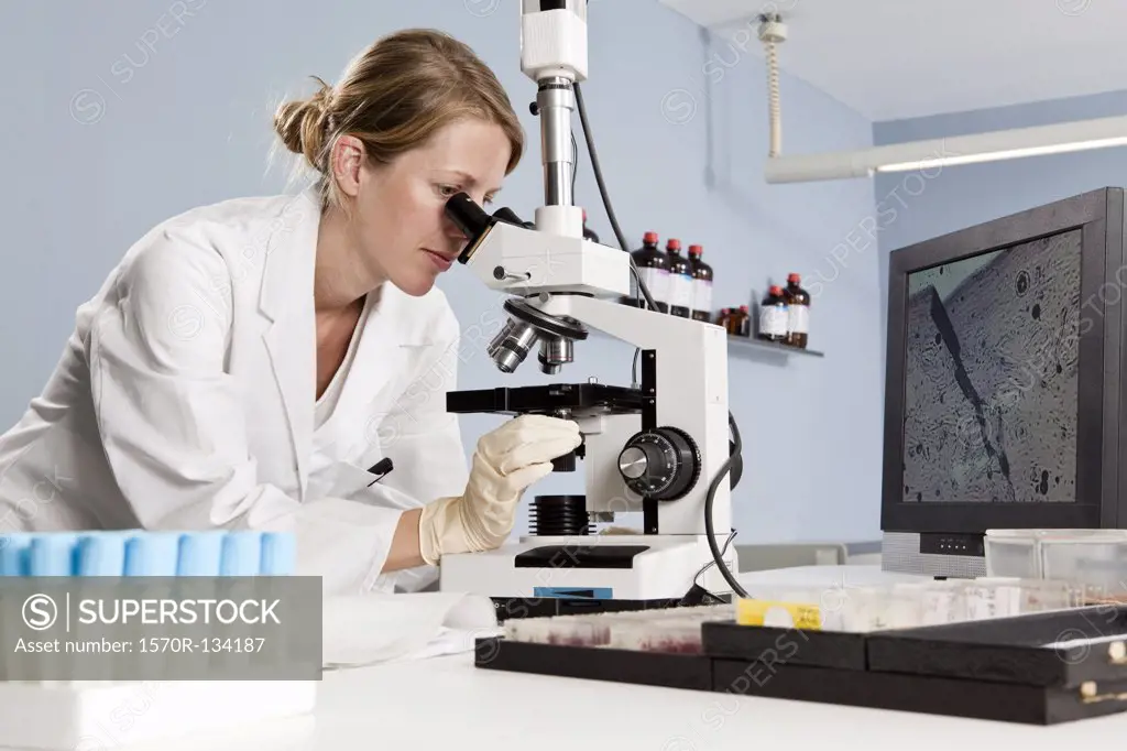 A lab technician looking into a microscope in a laboratory