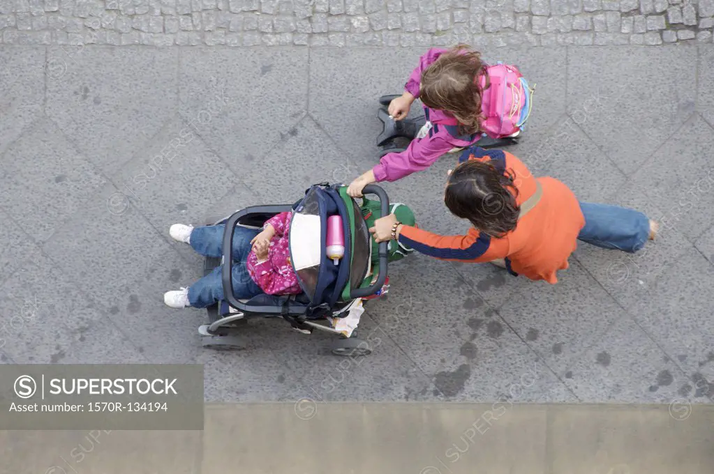 A mother and daughter pushing another daughter in a stroller