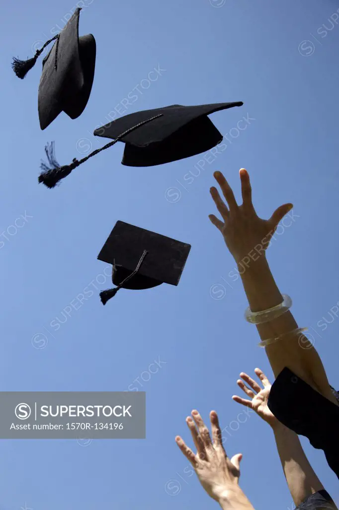 Three mortarboards being thrown