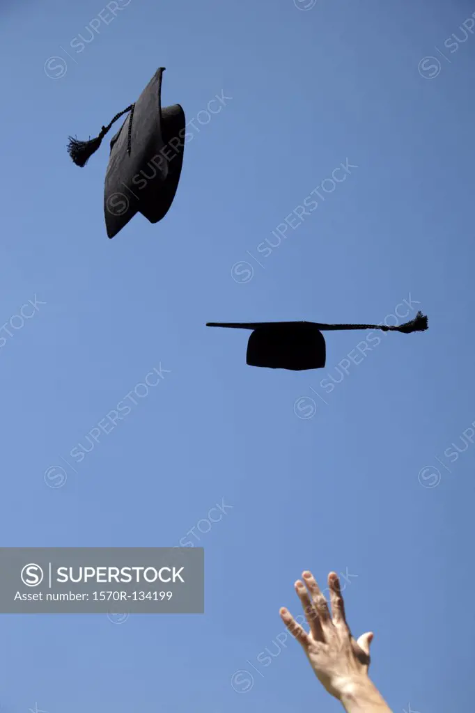 Two mortarboards being thrown