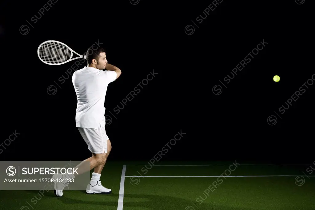 A tennis player about to a hit a ball, studio shot, portrait