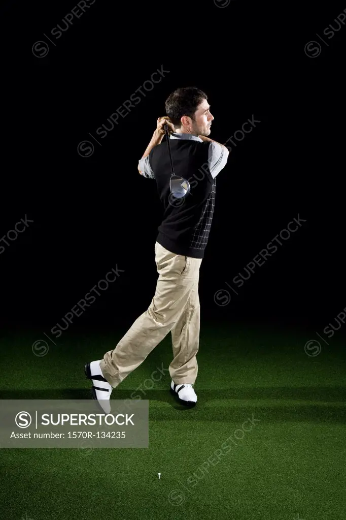 A golfer swinging a club, portrait, studio shot
