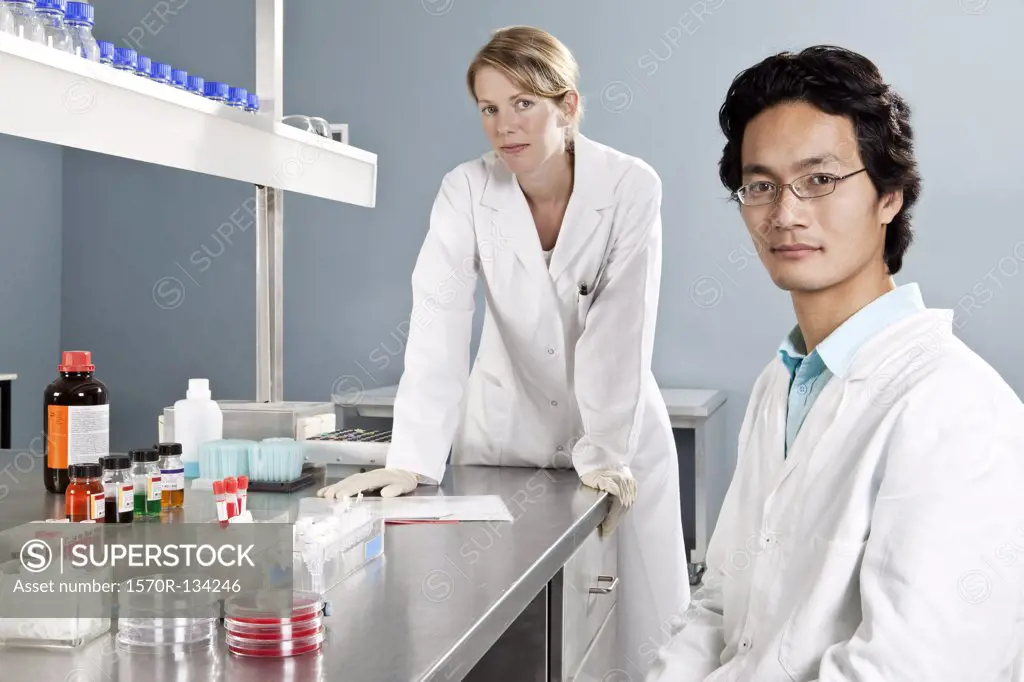 Two lab technicians in a laboratory, looking at camera