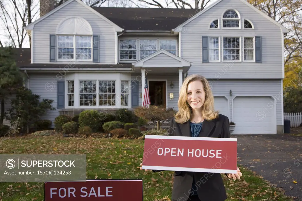 A real estate agent holding an OPEN HOUSE sign