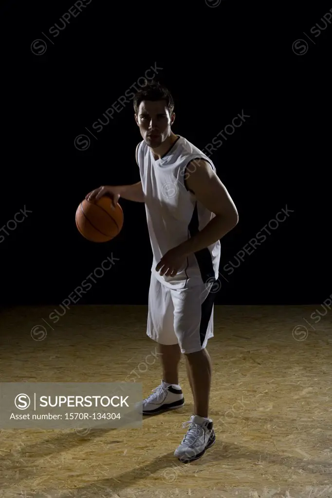 A basketball player dribbling a ball, portrait, studio shot