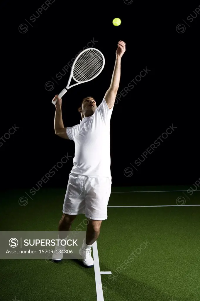 A tennis player serving a ball, portrait, studio shot