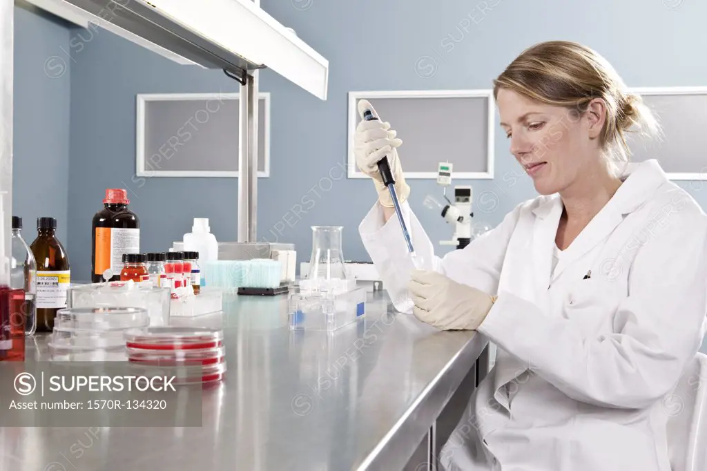 A lab technician using a pipette to put a sample into a vial