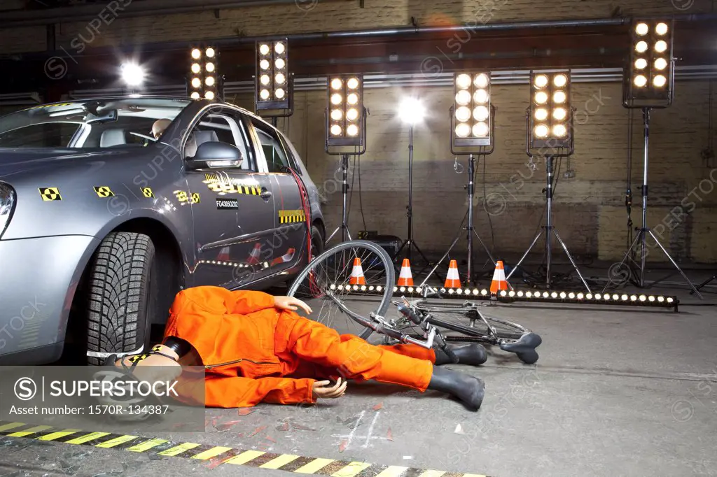 A crash test dummy on ground after bicycle crashed into car