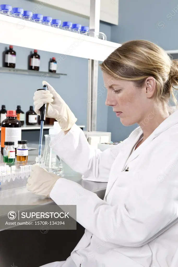 A lab technician using a pipette to put a sample into a test tube