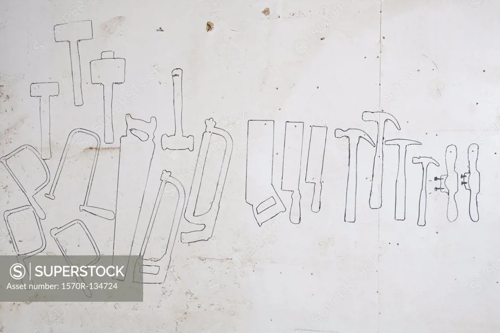 Drawn outlines of hand tools on a wall
