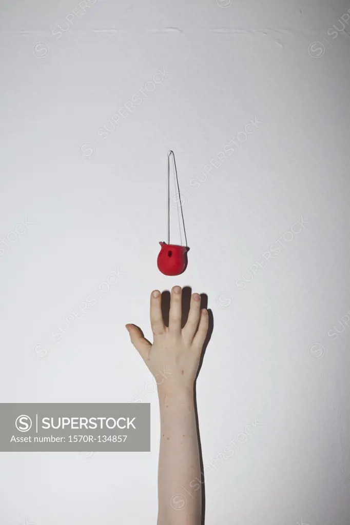 A hand reaching up a wall for a clown's nose