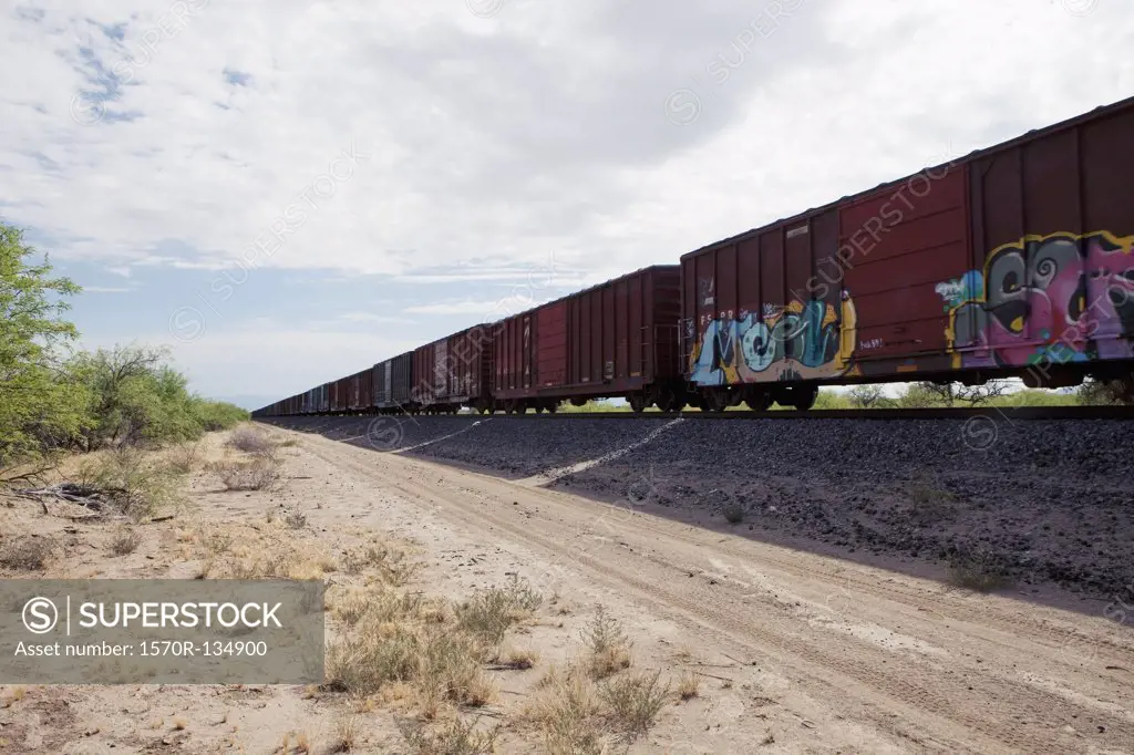 Freight train next to a dirt road