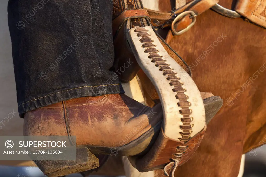 A cowboy boot in a horse stirrup, detail