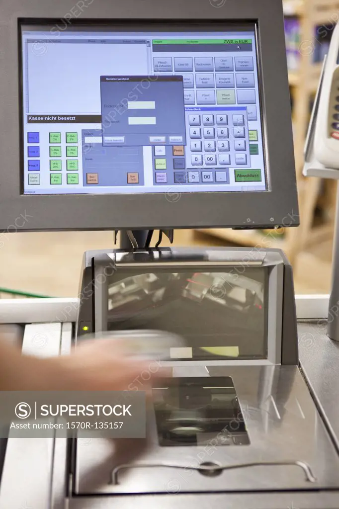 A cashier scanning groceries at a supermarket, focus on hand