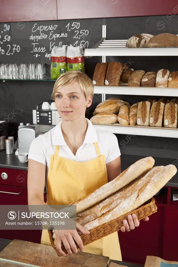 A sales clerk holding a basket of baguettes