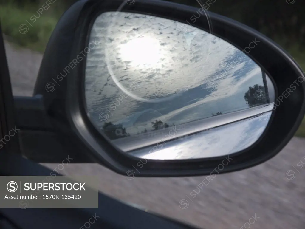The reflection of the sky in a car side-view mirror