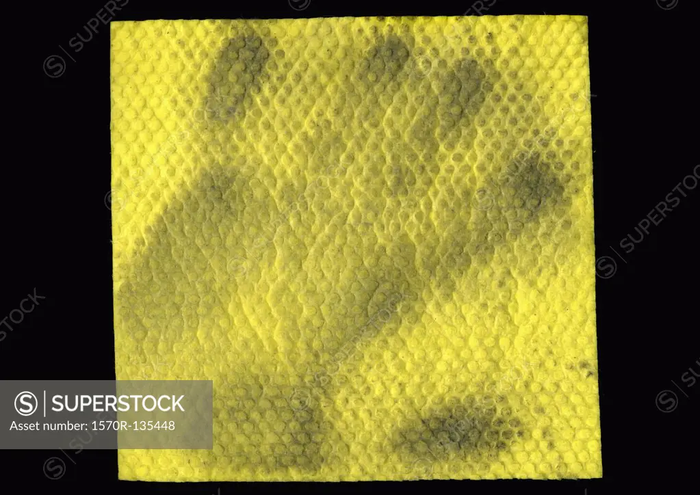 A yellow sponge cloth with a dirty handprint on it