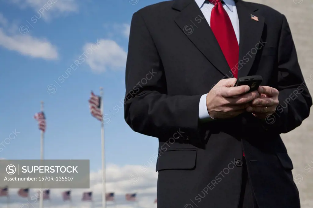 A man text messaging, American flags in the background