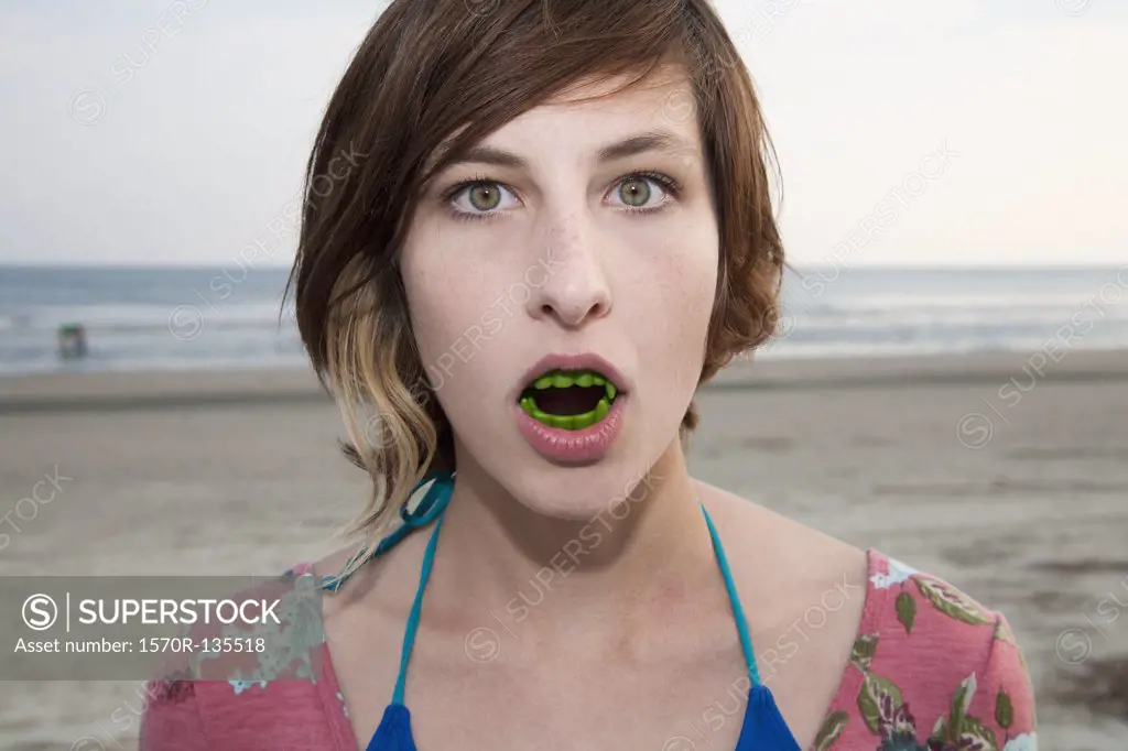 A woman wearing vampire teeth at the beach, portrait