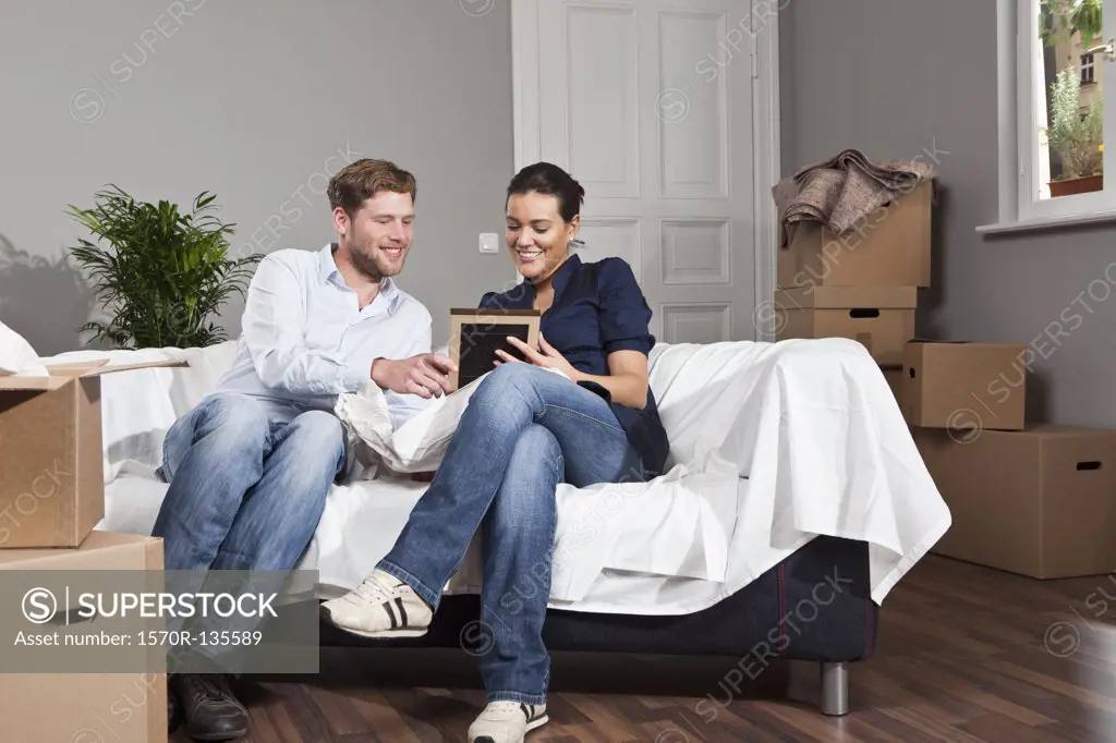 A couple sitting on a sofa looking at a picture frame