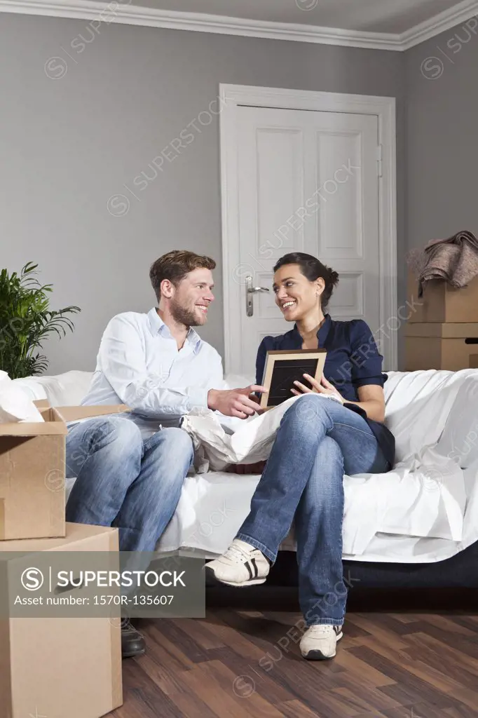 A couple sitting on a sofa looking at a picture frame