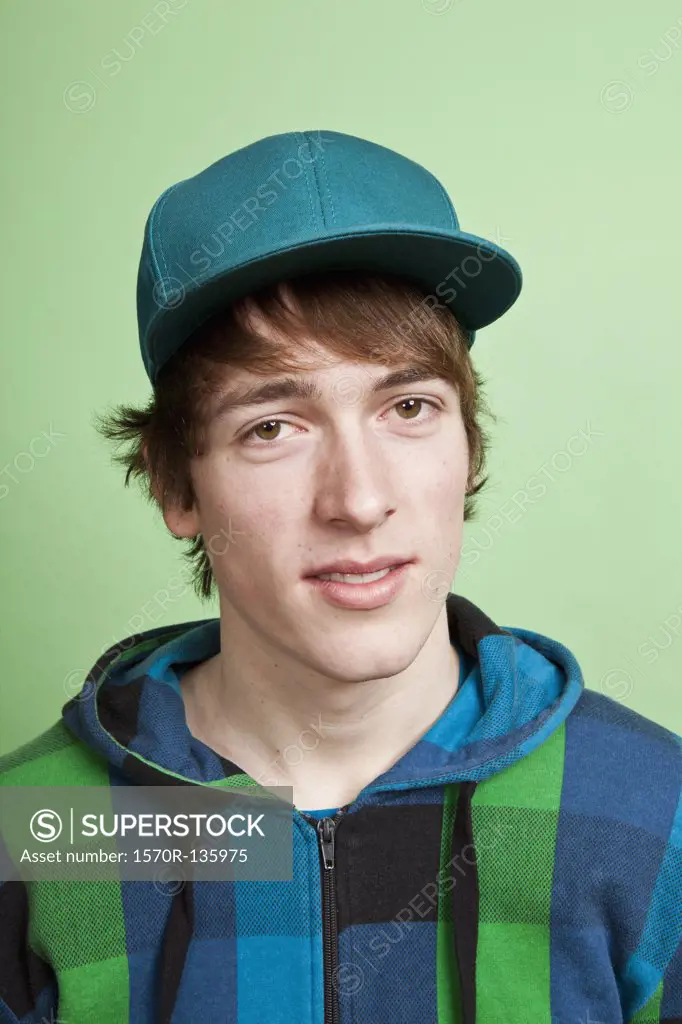 A teenage boy wearing a hoodie and baseball cap, portrait, studio shot