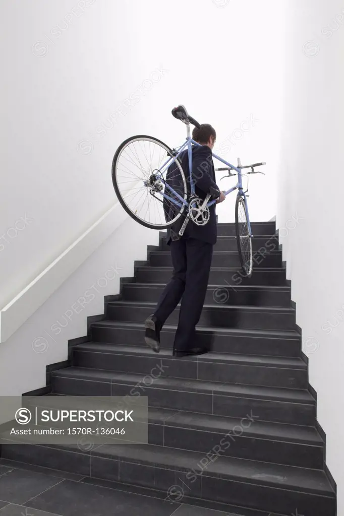 Business man returns home carrying bicycle up steps.