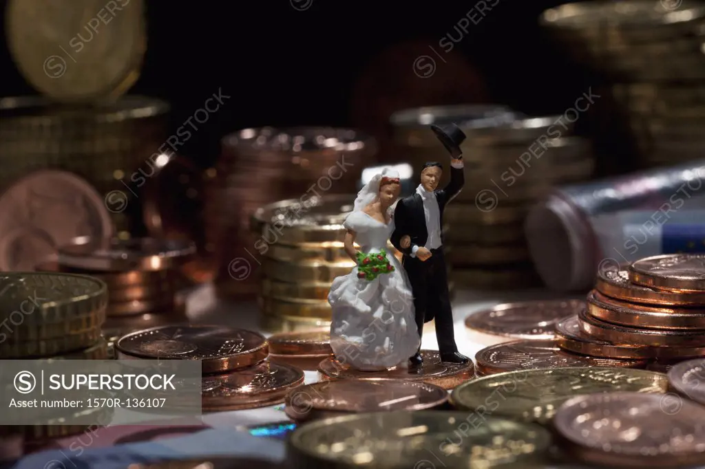 Miniature wedding couple figurines amidst stacks of European Union coins