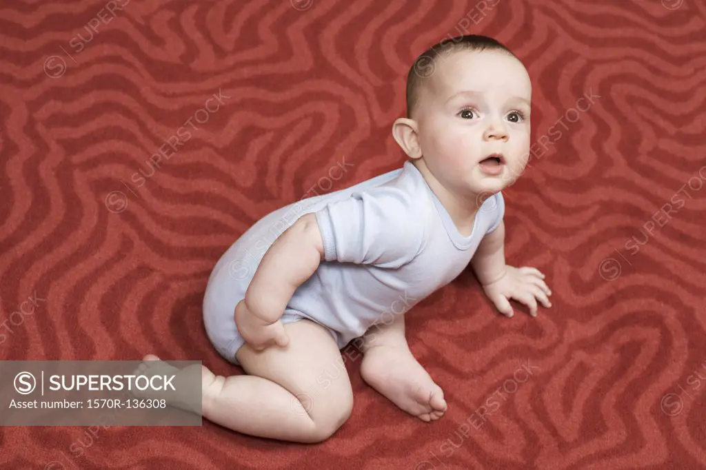 A baby boy lying on a patterned carpet