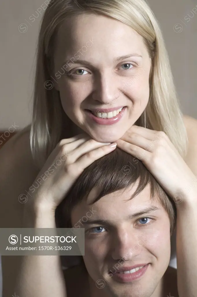 A woman resting her chin on top of her boyfriend's head, portrait
