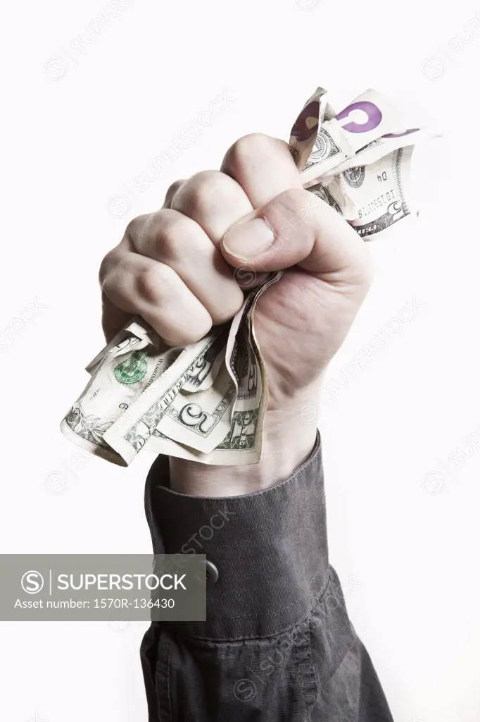 A man gripping a wad of US paper currency, close-up of hand