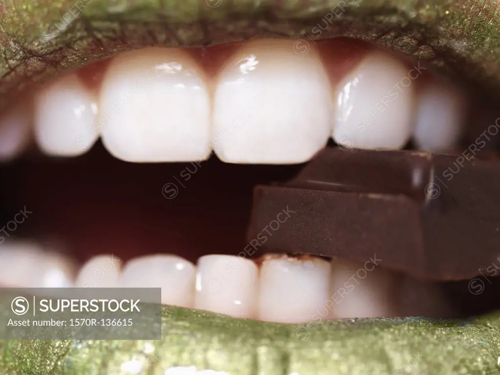 A woman eating a piece of chocolate, extreme close up of mouth