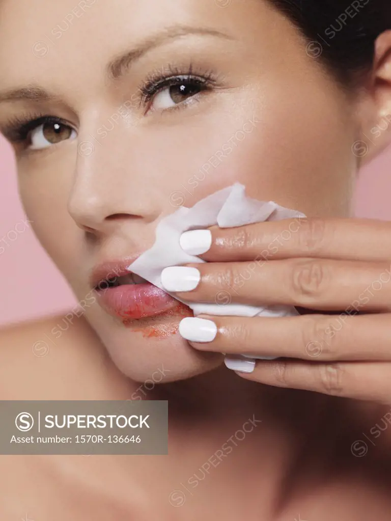 A woman wiping lipstick off with a tissue