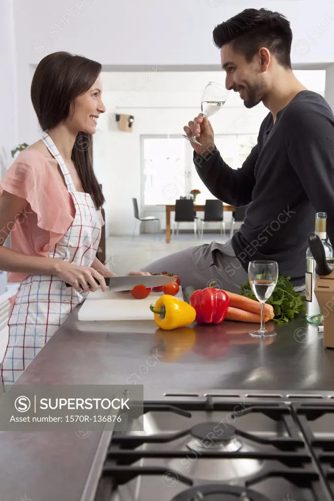 A young couple drinking wine and preparing food