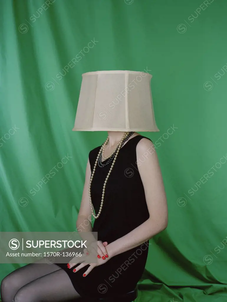 A well-dressed woman wearing a lamp shade on her head