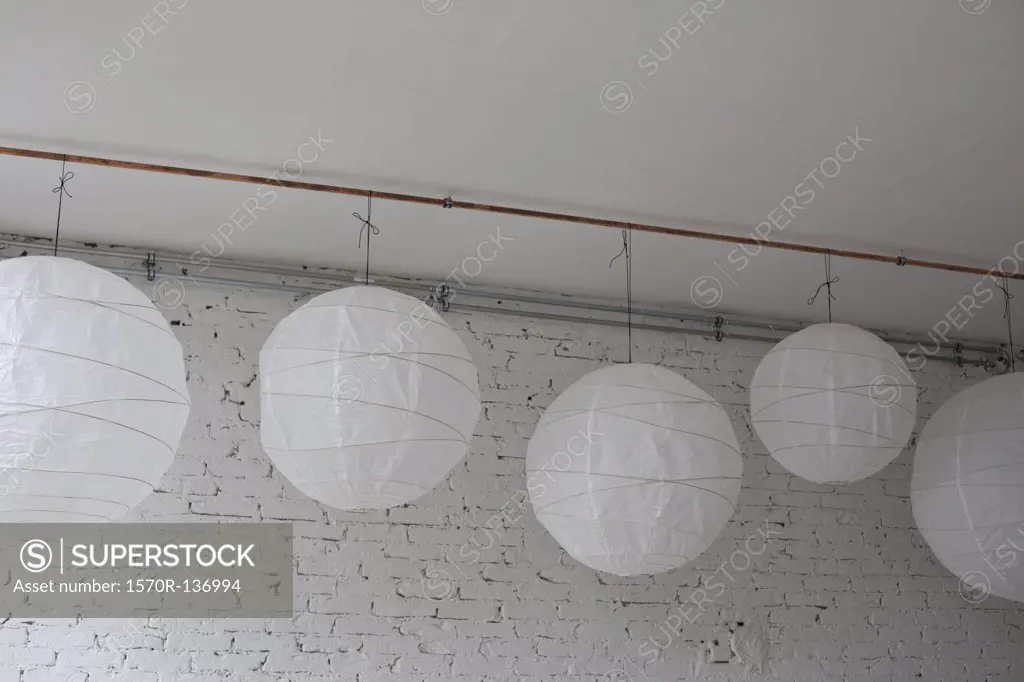 Five white round paper lanterns hanging in a row