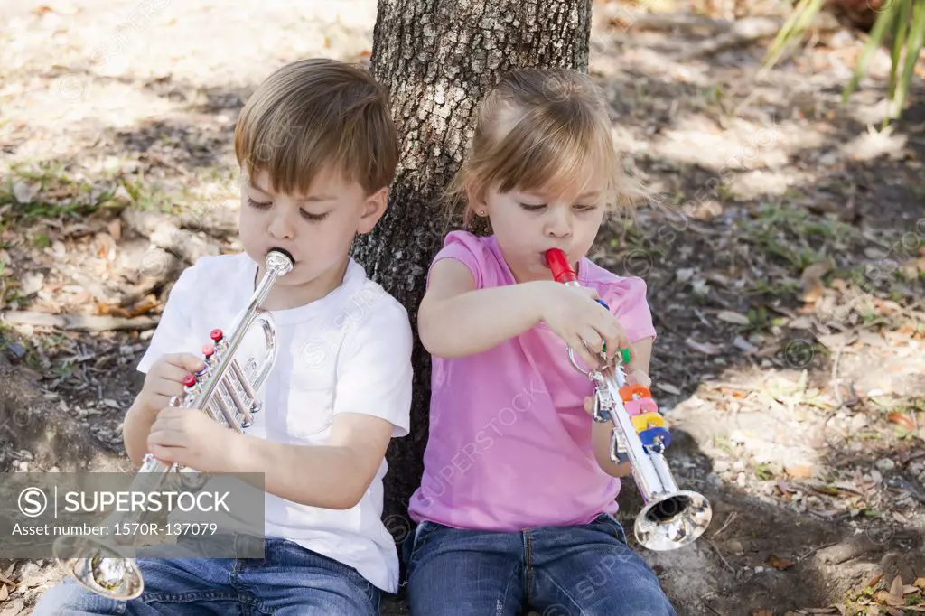 A boy and a girl sitting and playing toy musical instruments