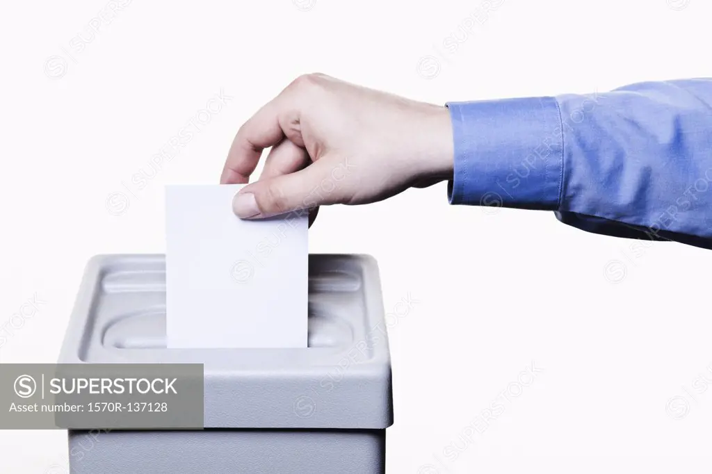 A man putting a blank white ballot into a ballot box, close-up hands