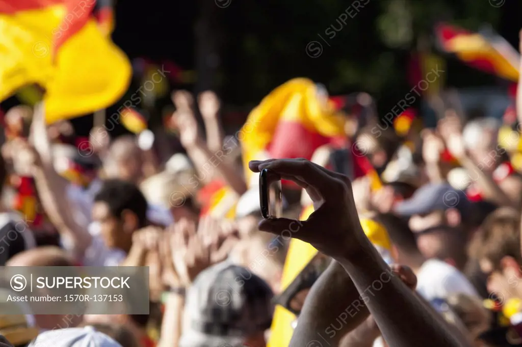 Detail of a person in a crowd holding a mobile phone
