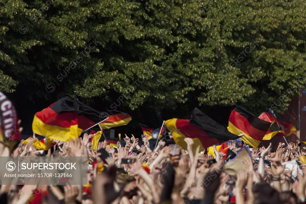 Detail of people in a crowd waving German flags