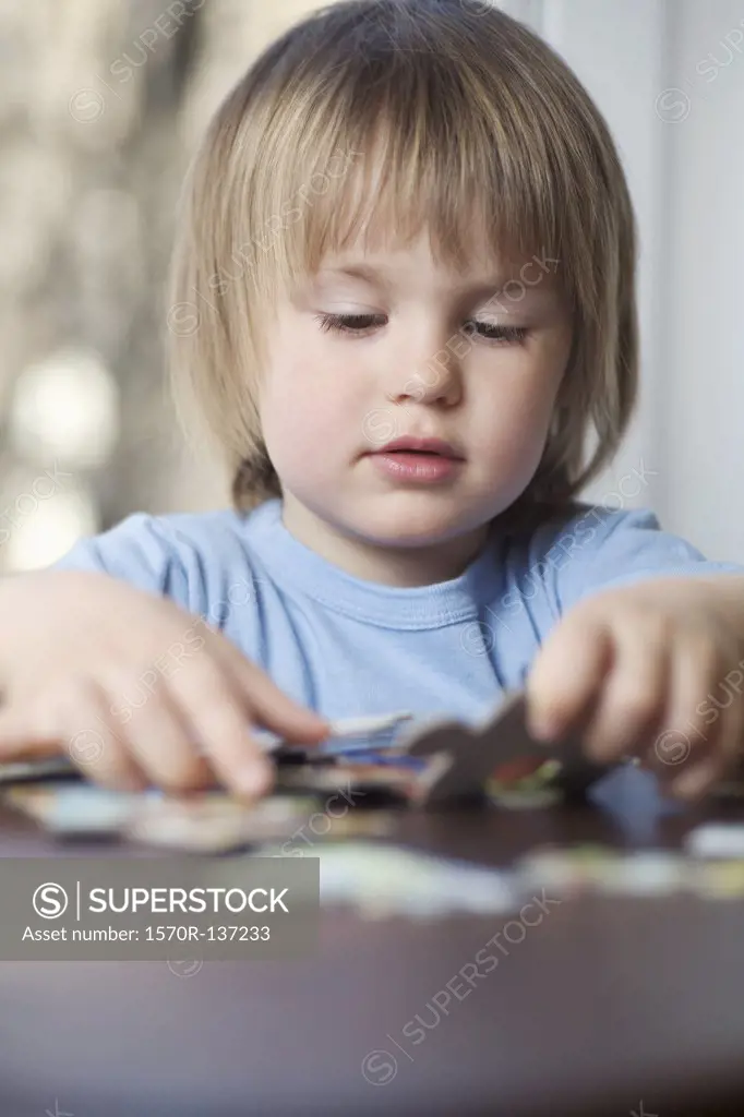A young boy picking up a puzzle piece