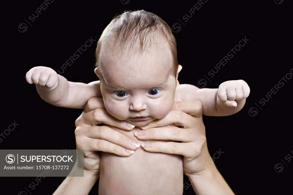A baby held aloft staring down