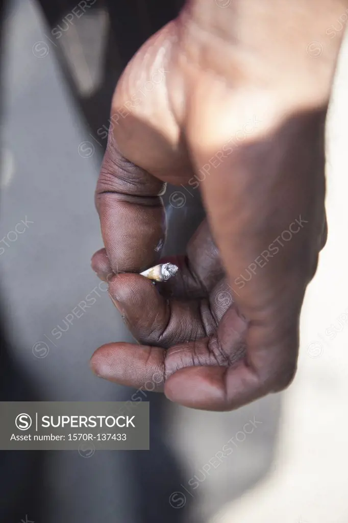 A dirty hand holding a cigarette